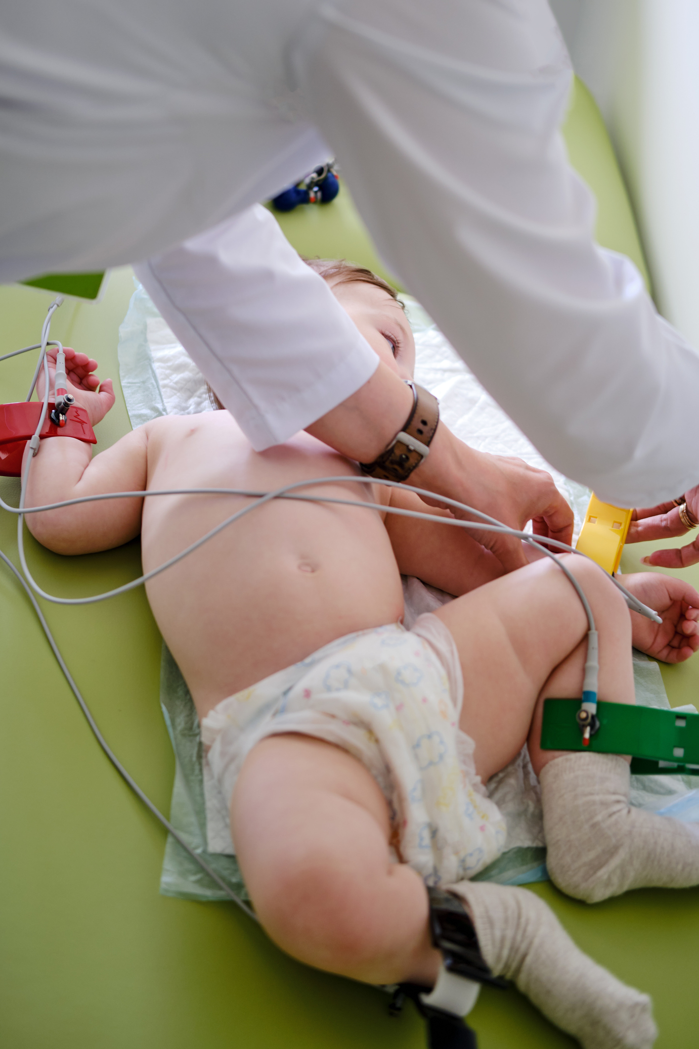 Doctor cardiologist pediatrician makes an electrocardiogram toddler baby boy. Doctor doing ecg to child checking heart health. Kid age one year (12 months)